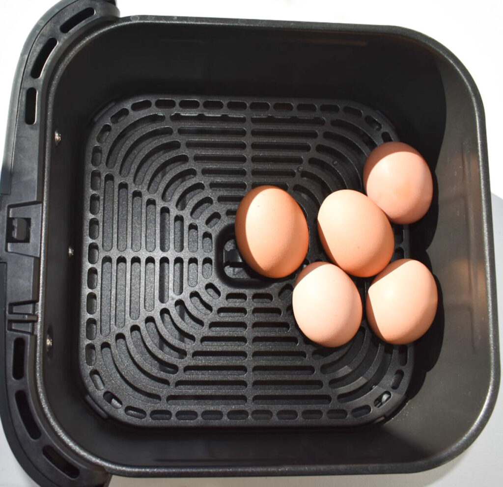 Five eggs placed in air fryer ready to be hard boiled