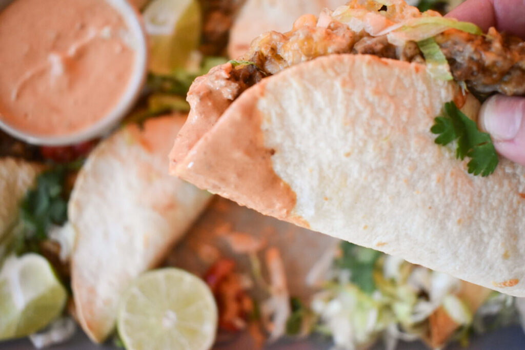 Sheet pan baked taco recipe dipped in creamy salsa