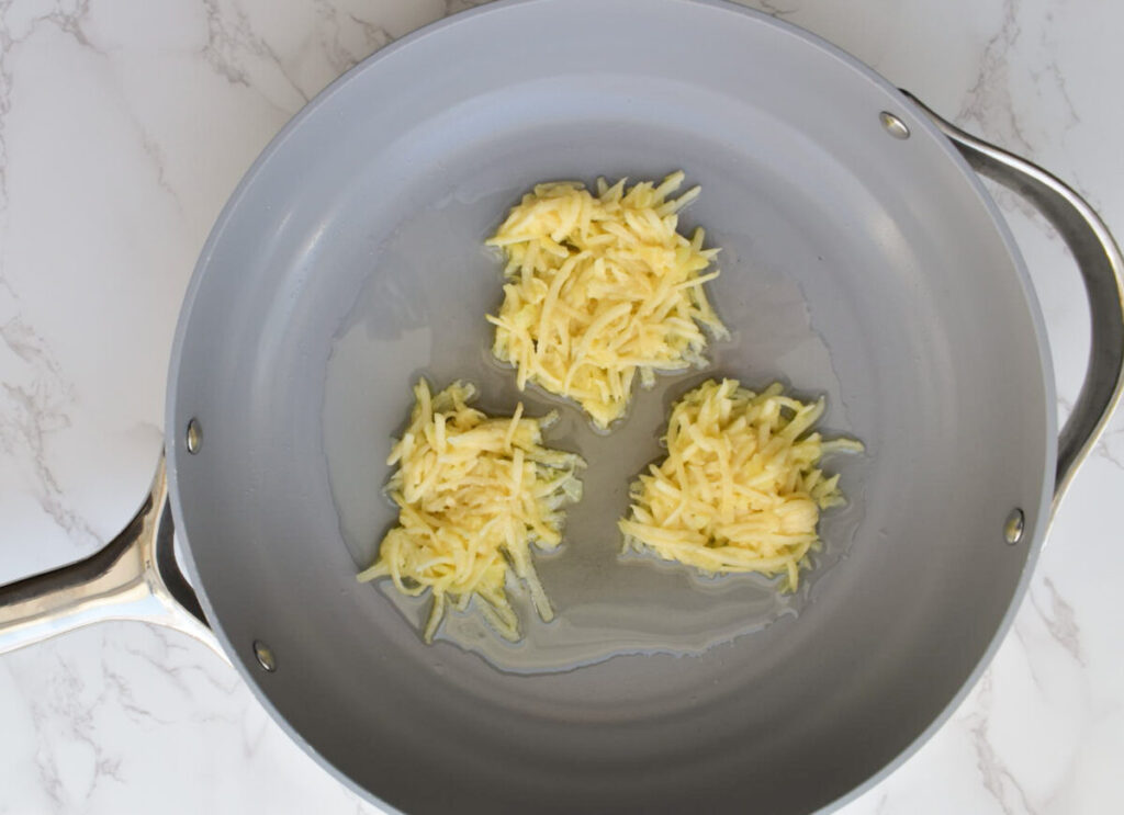 dollops of latke mixture in frying pan