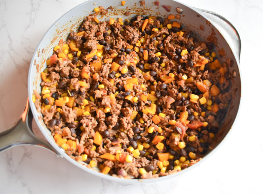 Saute pan with ground meat, beans, corn, for taco bake