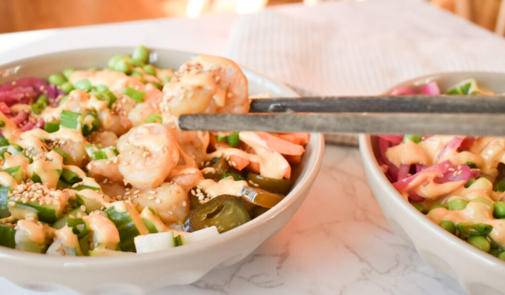 shrimp poke bowls made with rice, cucumber, carrots, and edamame